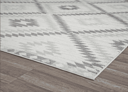 Alto texto: Alfombra decorativa en tonos gris y blanco con diseño geométrico sobre suelo de madera en oficina o sala de estar.
