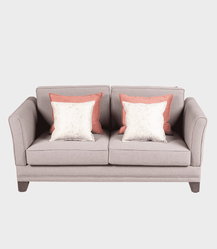 Sofá de tela en color gris claro con cojines decorativos en tonos rosa y beige, ideal para sala de estar, oficinas o zonas de descanso.