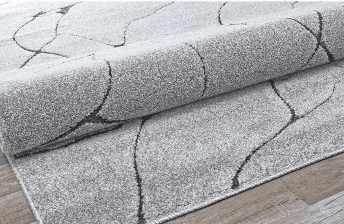 Suelo de madera con alfombra moderna gris clarita, decorativa, con patrones de líneas negras, en un ambiente interior elegante.