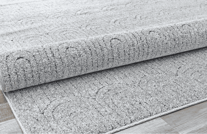 Suelo de alfombra gris con patrones decorativos, ideal para decorar espacios elegantes y confortables en hogares u oficinas.