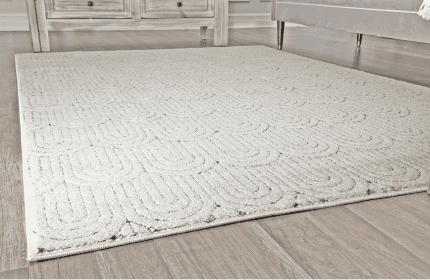 Suelo de alfombra beige con diseño geométrico en una sala moderna con muebles de madera y decoración acogedora.