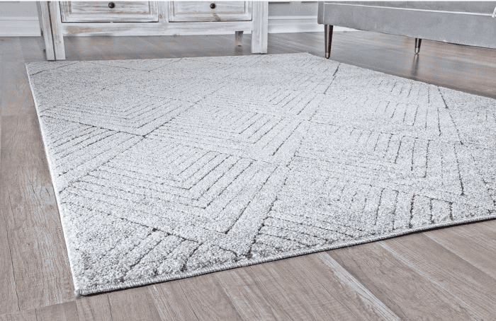Suelo de alfombra en zona de salas con muebles de madera y sofá gris.