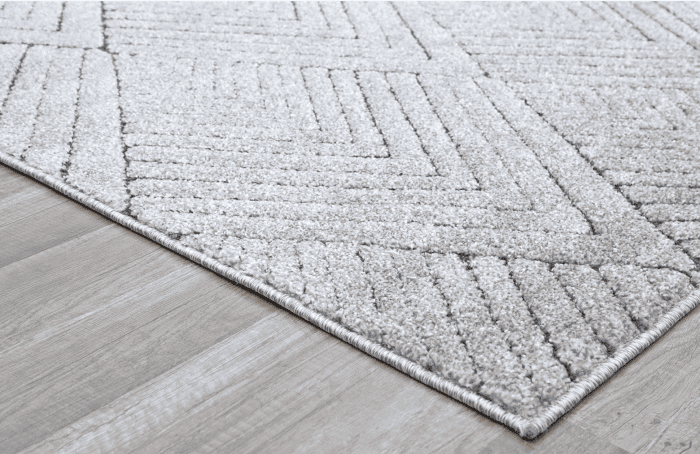 Suelo con alfombra en tonos grises y muebles de madera clara, decorada con sillones y escritorios modernos para espacios de trabajo y descanso.
