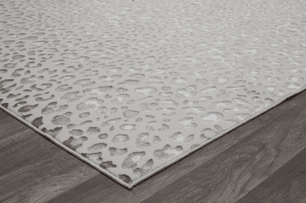 Suelo de alfombra con patrón de animal print en tonos cremosos y grises, sobre suelo de madera oscura. Perfecta para decoración moderna y elegante en salas o dormitorios.