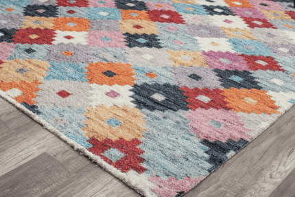 Colcha de alfombra de área de estilo bohemio con patrones coloridos en tonos naranja, rosa y azul en un ambiente moderno.