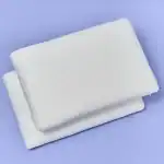 Alto texto: Juego de dos almohadas blancas con funda de textura suave, ideales para un descanso cómodo y decorativo en el hogar.