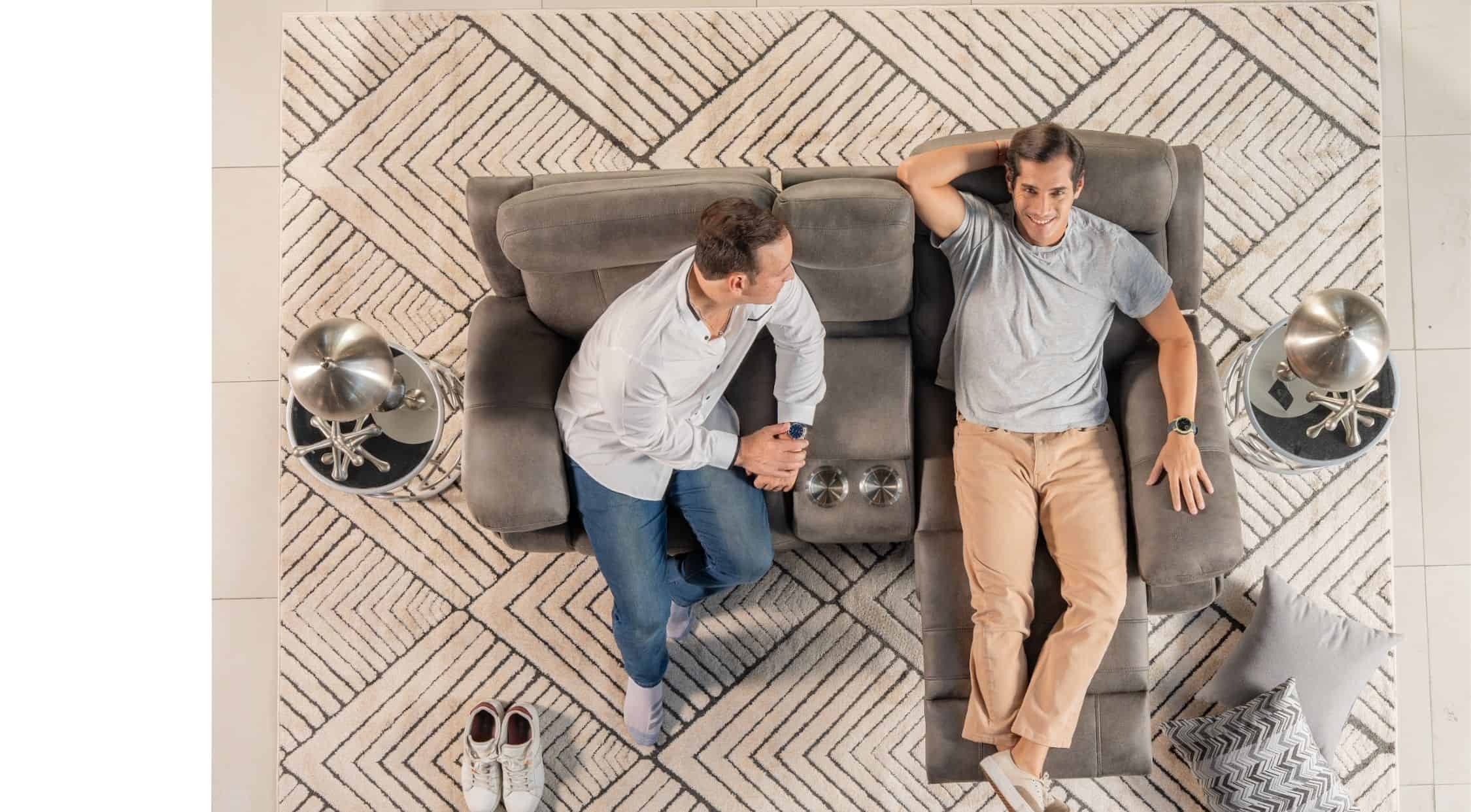 Cómoda sala de estar con sofá gris, mesas de noche con lámparas de diseño y un par de cojines decorativos, creando un ambiente acogedor y moderno.