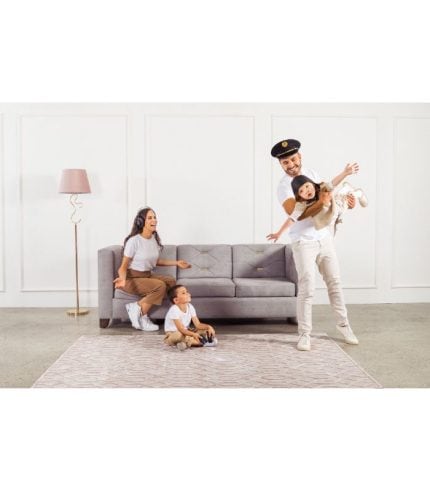 Cómodo sofá gris en un salón minimalista con paredes blancas y lámpara de pie rosa, ideal para zonas de muebles, decoración y sillones familiares.