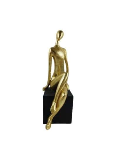 2. Figura decorativa de mujer dorada sentada en base negra.